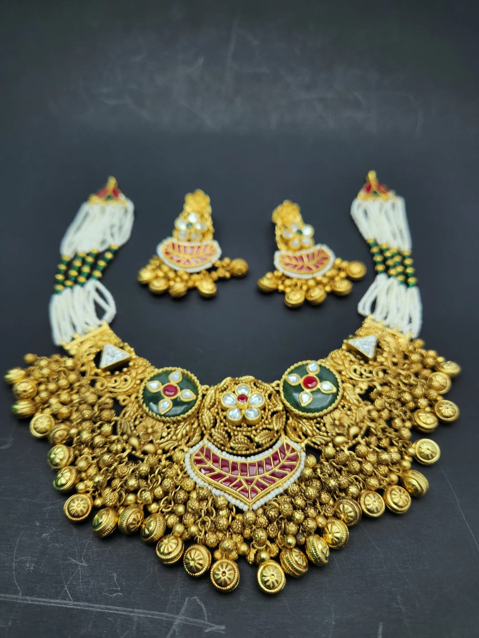 Bridal gold choker with bell clusters, green and red stone centre, pearl-bead side strands and matching earrings