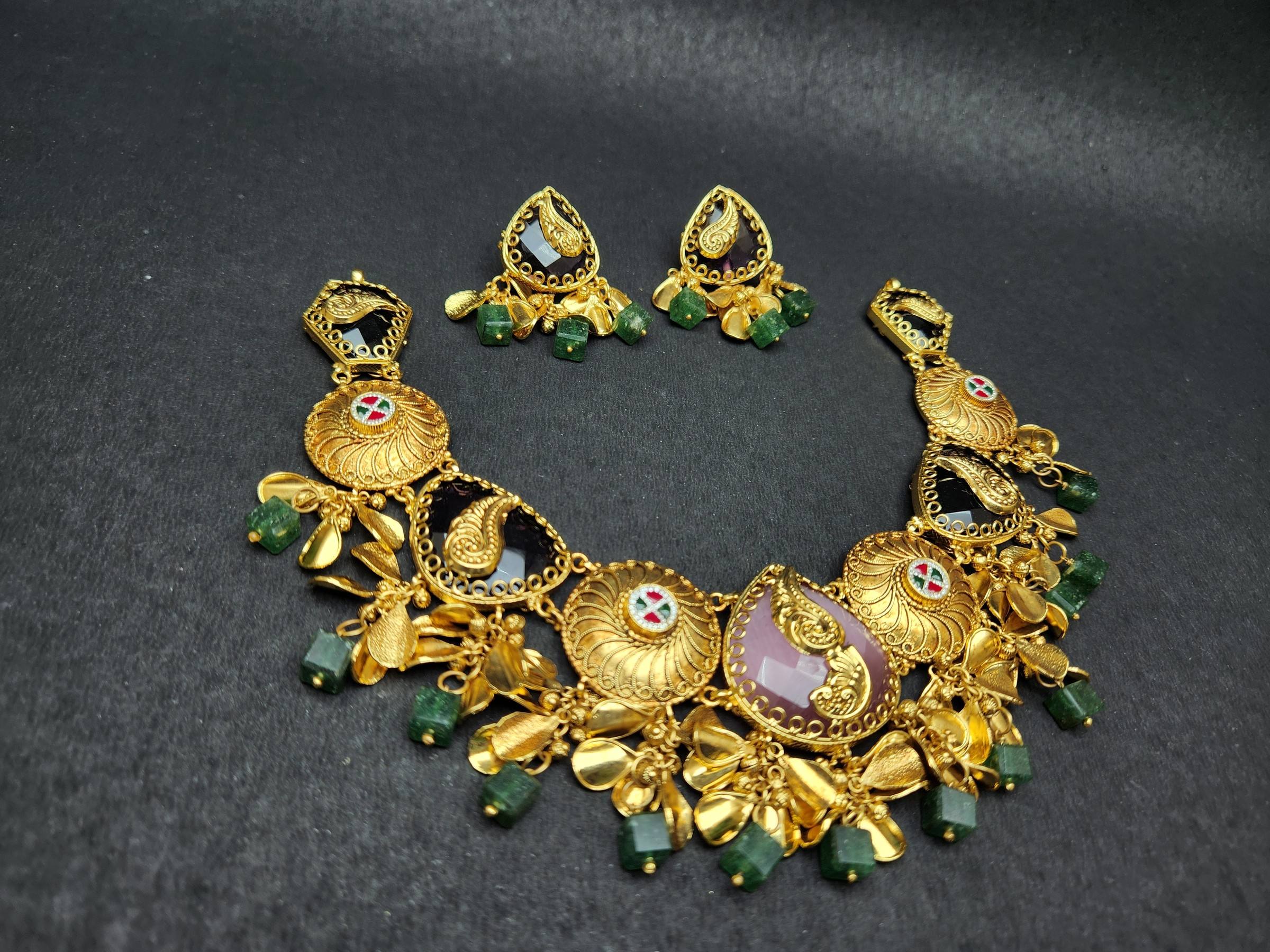 Gold necklace with paisley motifs on purple stones, swirl discs, gold petal and green bead fringe, matching earrings