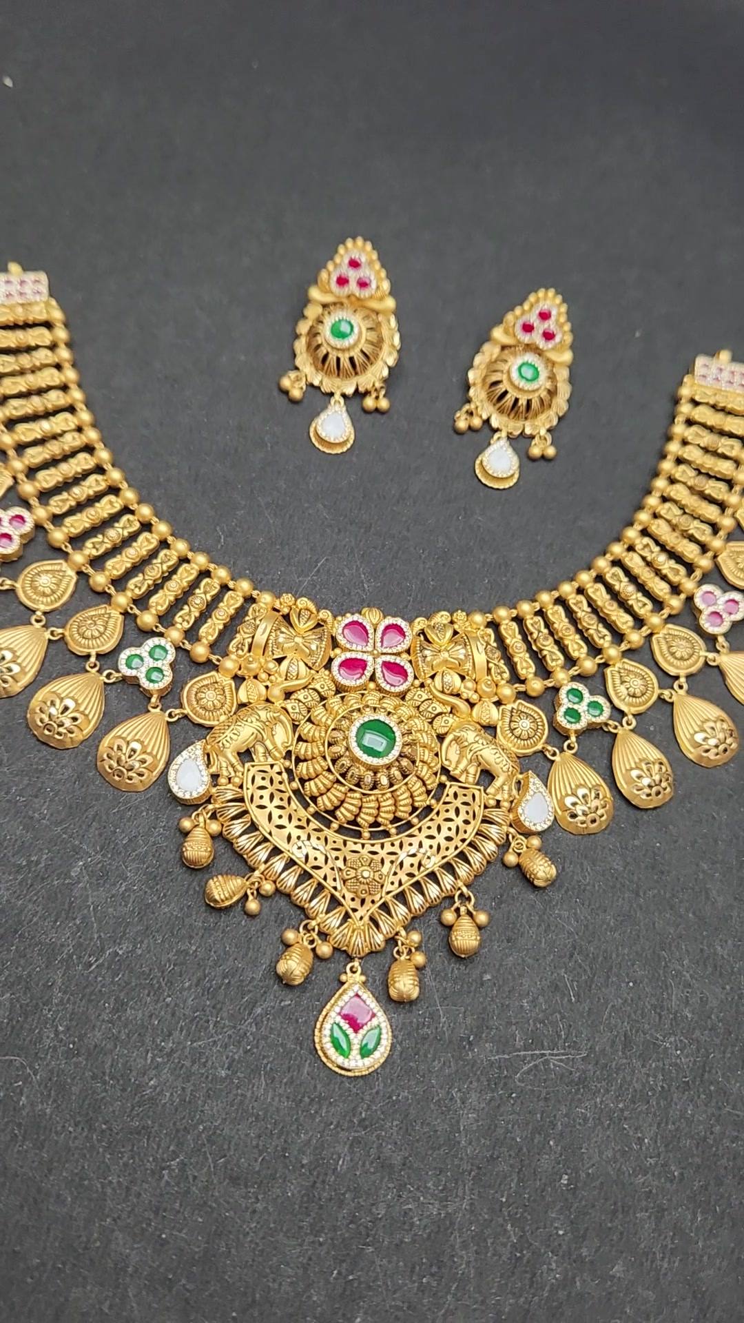 Matte gold collar necklace with ribbed bead columns, pink-stone lotus centre and matching earrings