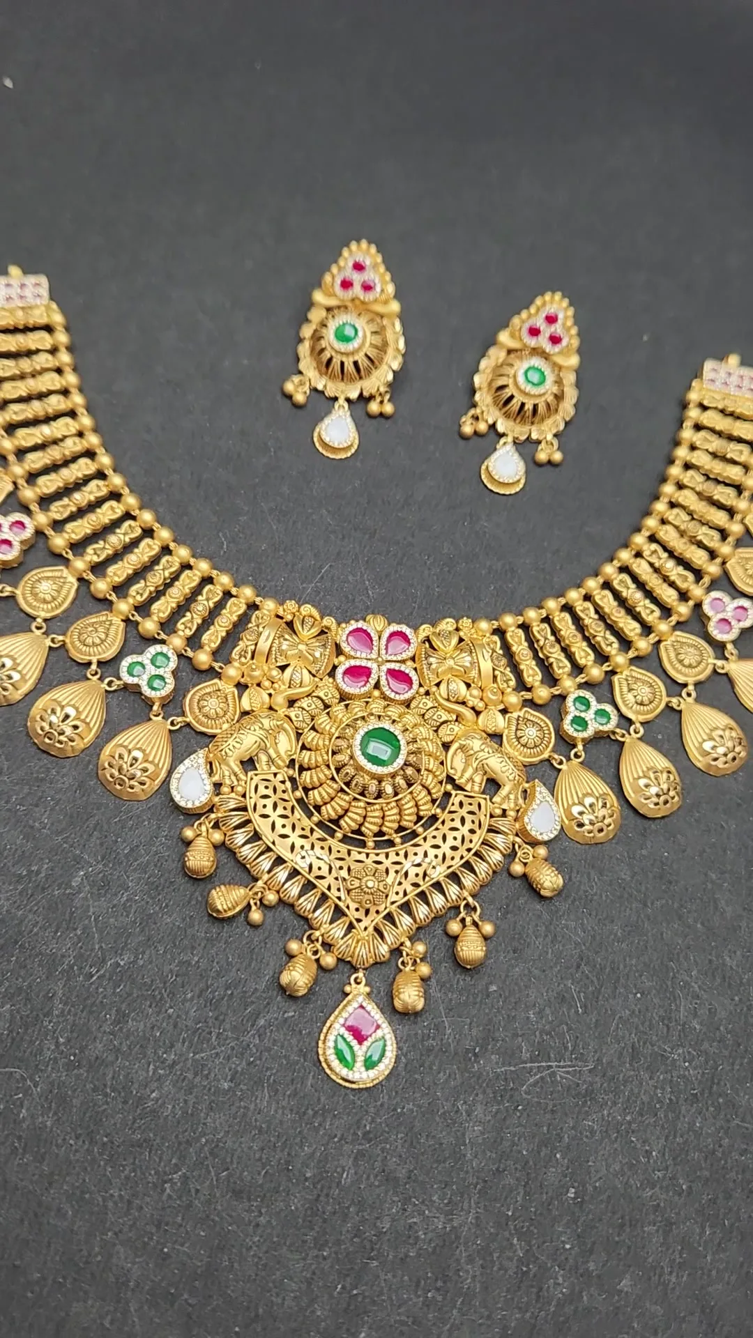 Matte gold collar necklace with ribbed bead columns, pink-stone lotus centre and matching earrings