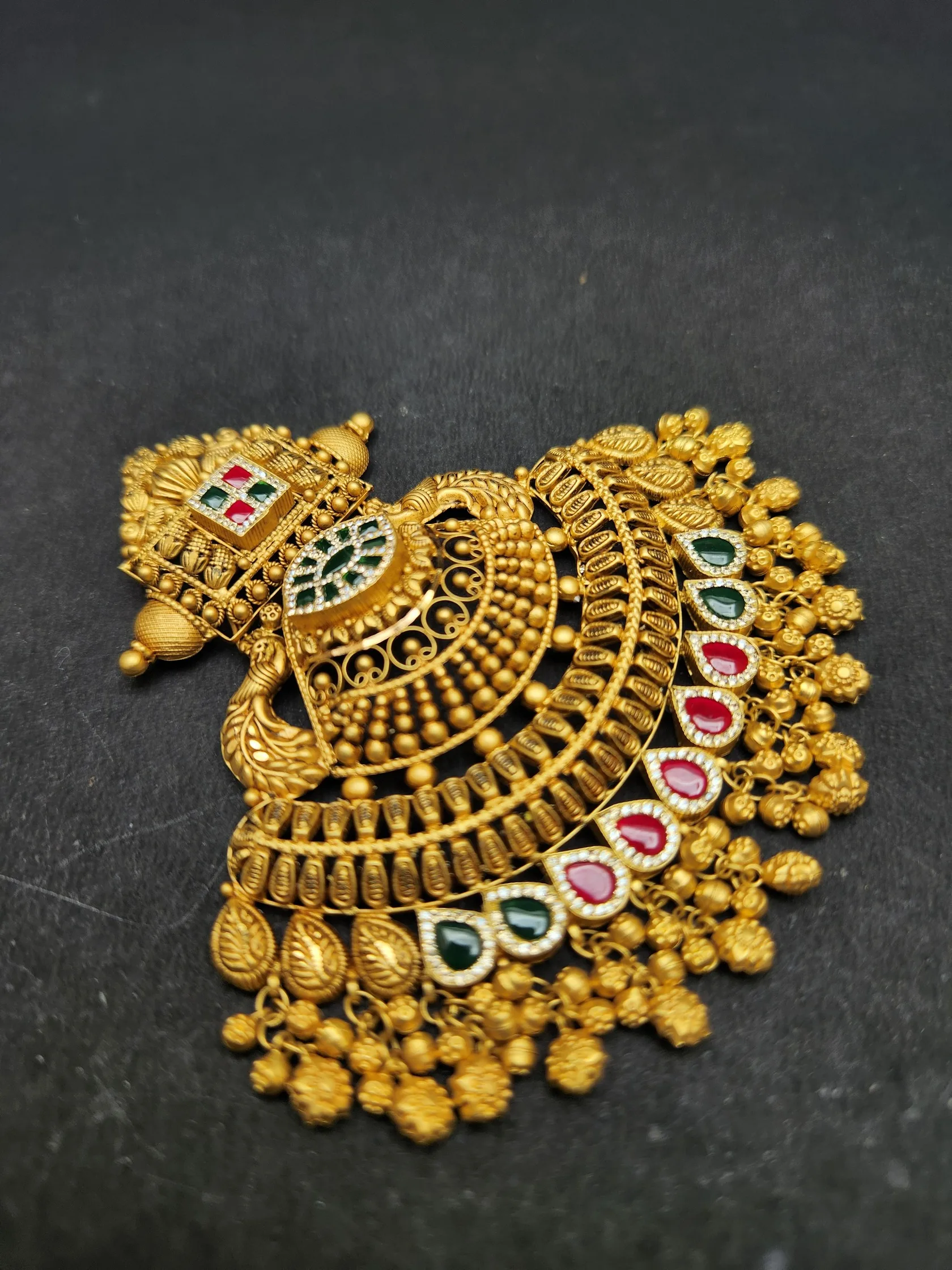 Peacock gold pendant with a fan of beaded arches, green and red drop-shaped stones and gold bead cluster fringe